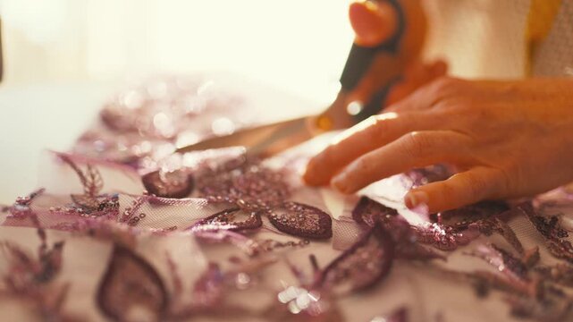 Tailor hands cutting sequin beaded lace fabric