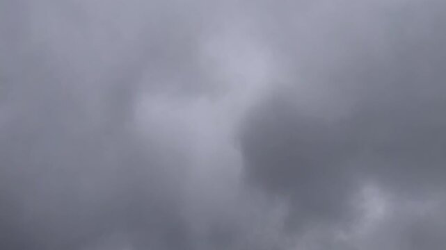 Dark storm clouds fast moving across an overcast sky timelapse. Atmospheric time lapse of dense gray clouds creating a dramatic natural weather background. 