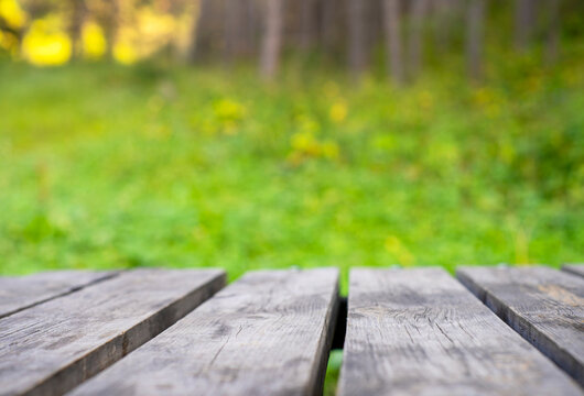 Empty wooden table surface against blurred mountain forest background with bright summer sunshine and copy space