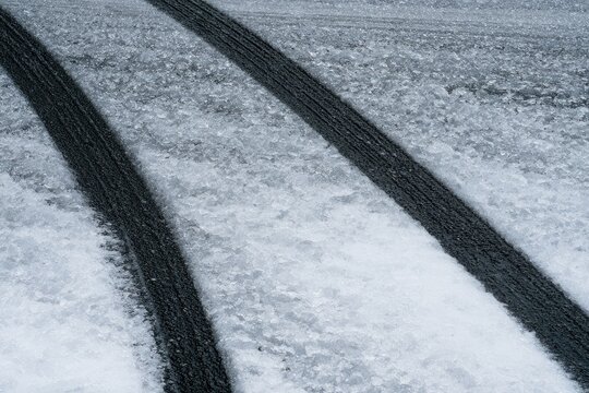 Black tire tracks on a glistening, textured icy surface