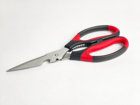 Multipurpose kitchen shears with sharp stainless steel blades, bottle opener feature, and ergonomic red and black handles, isolated on a white background.