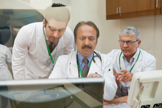 Doctors looking at CT scan on computer screen