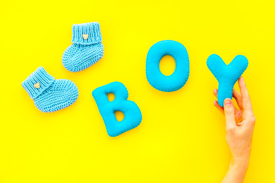 Children's birthday concept. Word boy near booties on yellow background top view