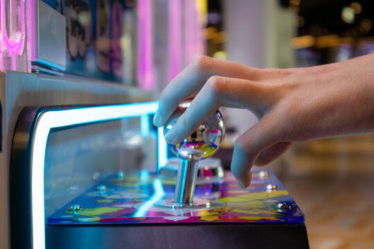 Anticipation and thrill captured in the suspended touch; vibrant arcade surface and polished chrome reflect neon energy
