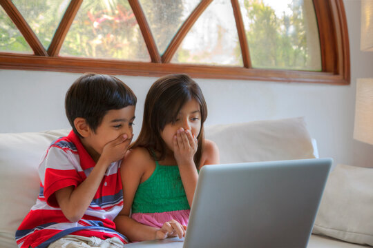 Brother and sister shocked while looking at laptop