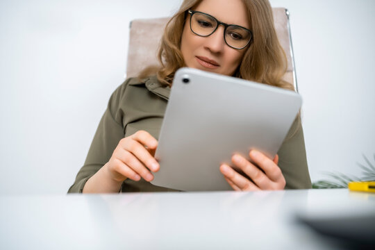 Closeup portrait of woman wearing glasses using digital tablet indoors. Visual content consumption wireless digital technology.