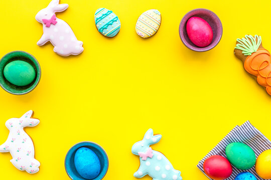 Sweets for celebrate Easter. Gingerbread in shape of easter bunny and easter eggs. Yellow background top view copy space