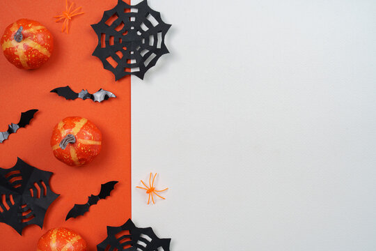 Halloween paper cut decorations on split orange and white background with copy space