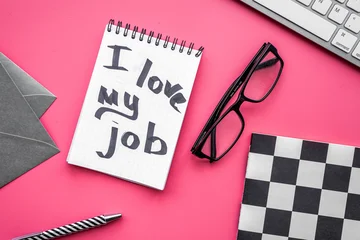 Find dream job. Handwritten motto I love my job in notebook on office desk on pink background top view © 9dreamstudio