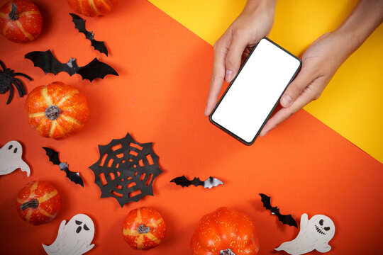 Hands holding smartphone with blank screen for Halloween mobile app mockup and AI technology