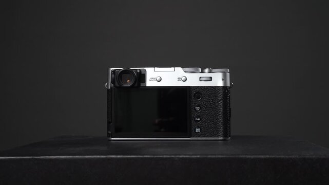 Silver and black vintage style digital mirrorless camera on a dark background and studio shot of photography equipment