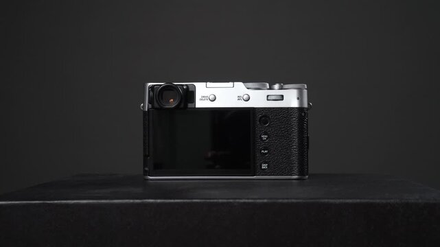 Silver and black vintage style digital mirrorless camera on a dark background