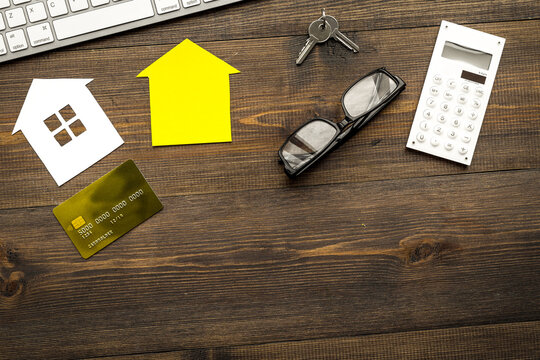 selling property online with paper house on office desk wooden background top view mockup