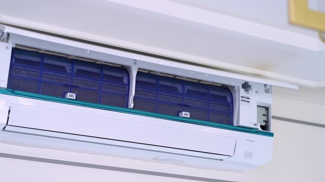 Open wall mounted air conditioner showing blue air filters for cleaning and home appliance maintenance