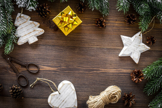 New year's background. Christmas toys, present, spruce branches, pine cones on dark wooden background top view copyspace