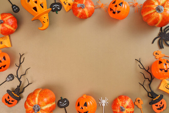 Halloween frame concept with pumpkins witch hat spiders and copy space on brown background