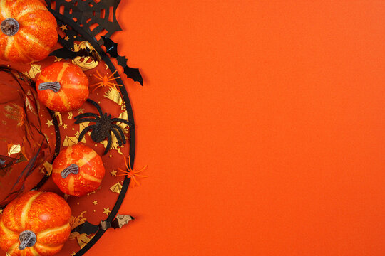Halloween border concept with pumpkins witch hat and spiders on orange background