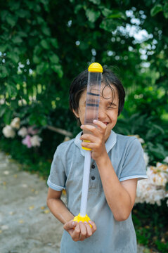 A happy boy plays with a water toy outdoors in the summer garden