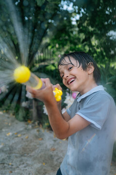 A happy boy plays with a water gun outdoors