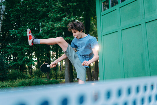 Teenage boy performs a trick shot while playing table tennis