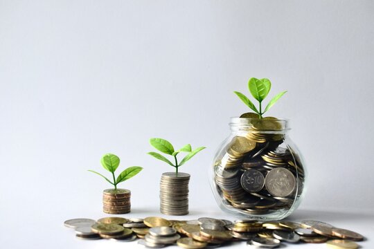 Close-up macro view of Malaysian sen coins scattered around growing stacks and a glass savings jar, highlighting regional currency and detailed financial investment concepts.