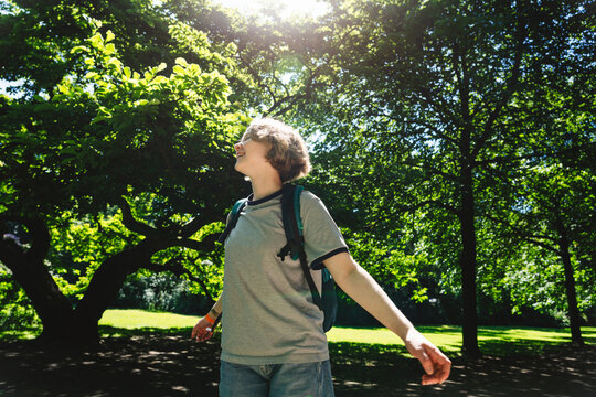 A happy girl enjoys nature while spinning in a sunny park