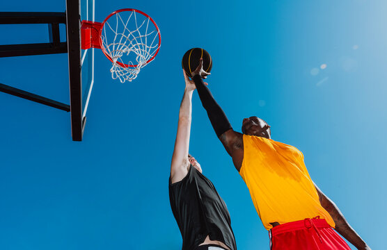 Basketball players jump for the ball during an outdoor match
