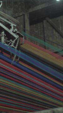 Colorful threads running through loom in dim mill