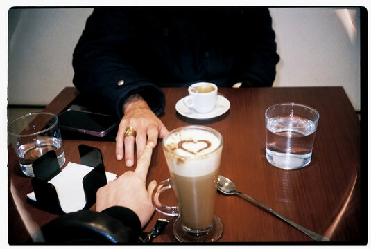 Couple holds hands during a romantic coffee date