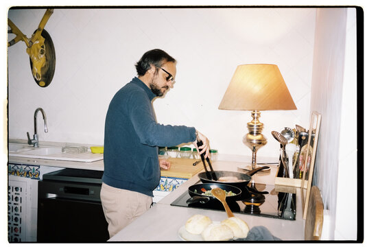 Adult man cooks dinner on the stove indoors at home