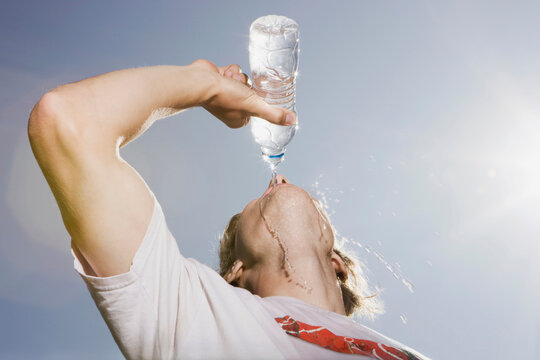 Germany, Berlin, Young man drinking water from bottle, portrait