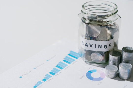 Glass jar with coin savings on financial graph report showing hopeful and optimistic feeling for future wealth growth and investment