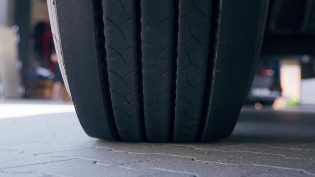 Detailed close-up view of a car tire tread on pavement showing rubber texture and wear outdoors.