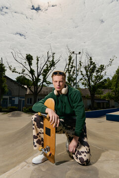 Handsome young man posing at the skatepark under a cloudy sky