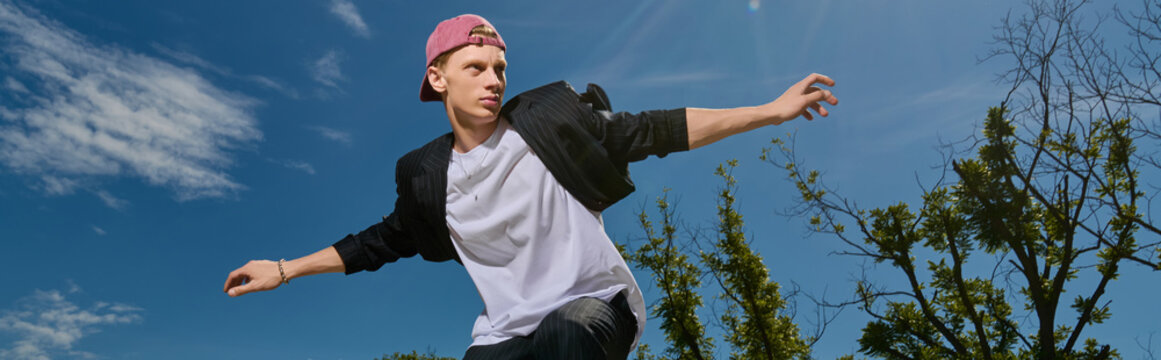 Young man showcasing his skateboard skills under a bright blue sky at a vibrant skatepark