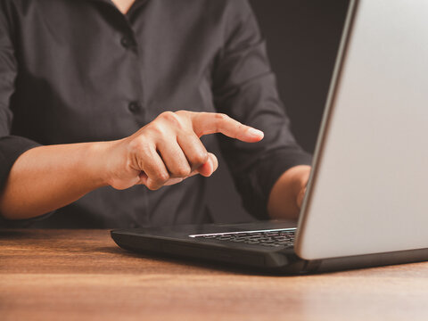 Person Pointing Toward Laptop Screen at Desk
