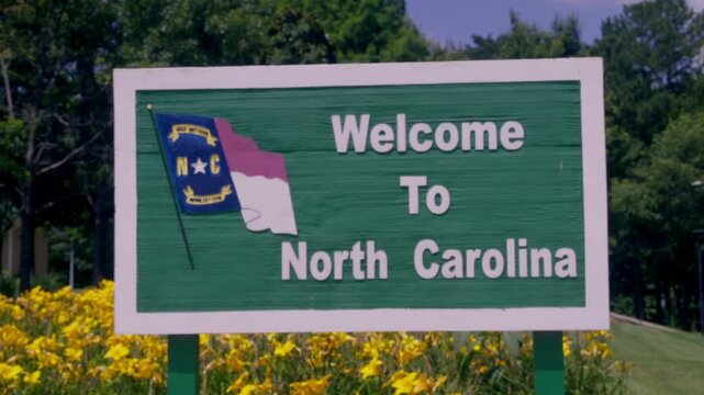 Welcome to North Carolina sign at rest area with video rack focus.