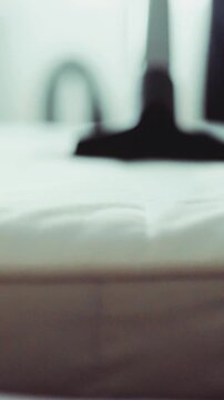 A macro shot of a vacuum cleaner brushing over a white mattress