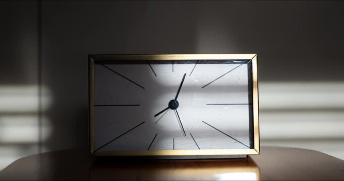 Timelapse of vintage gold desk clock with moving sunlight and window blind shadow