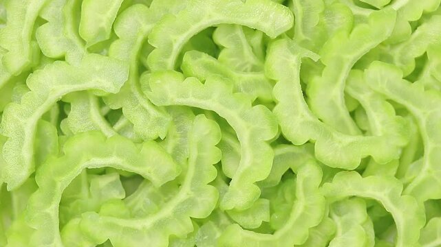 Pile of thinly sliced raw Chinese bitter melons slowly rotating. Top view