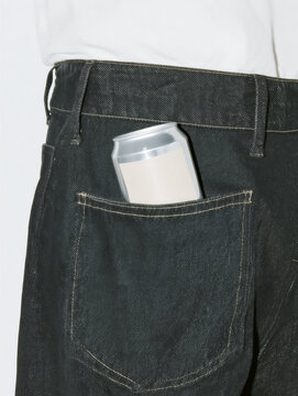 Soda can peeking out of back pocket of jeans on young man in white t-shirt. Lemonade beverage in a sealed aluminum container.