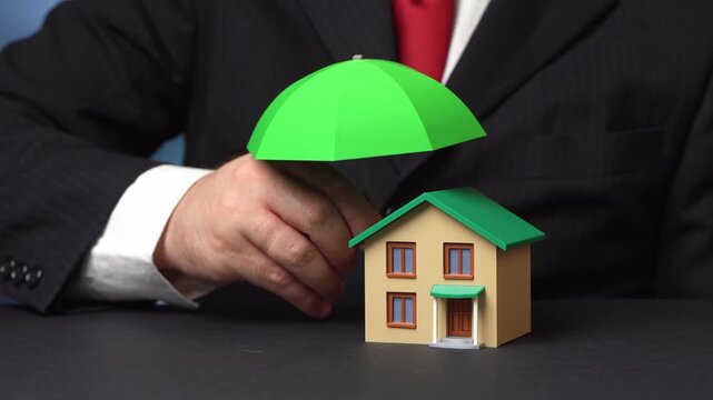 A house under a green umbrella. Property and real estate insurance with damage compensation. Financial protection safeguards homeowners from risks while ensuring security