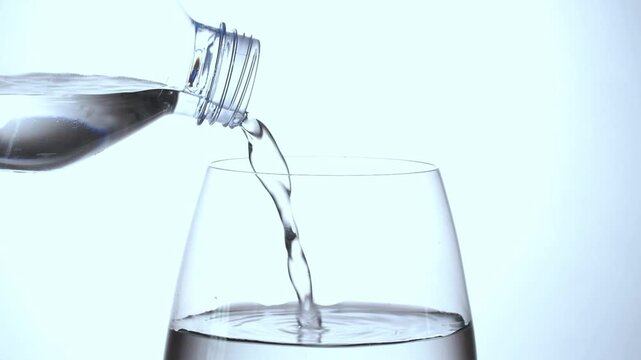 Crystal clear water being poured into a glass against a clean bright background.