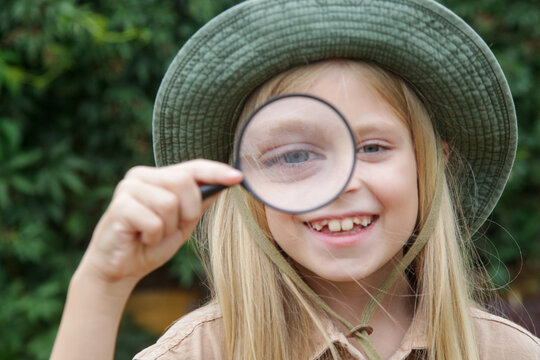 Candid Portrait of Curious Girl Playing with Magnifying Glass
