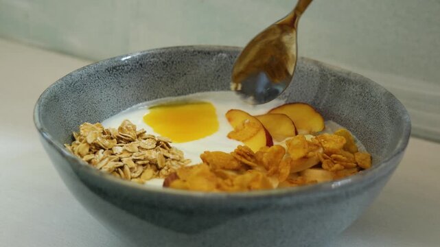 Person mixing a healthy breakfast bowl of granola and cornflakes