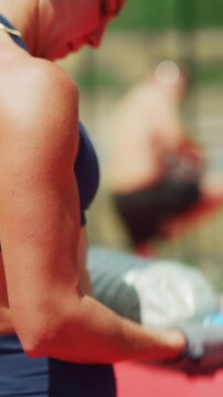 A fit woman engages in an intense bicep curl exercise using a large plastic bottle as a weight. Her focused effort highlights strength and dedication during an outdoor fitness training session.