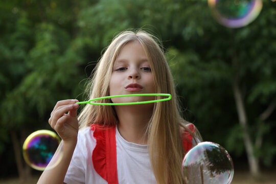 Happy little girl blowing soap bubbles on a sunny summer day