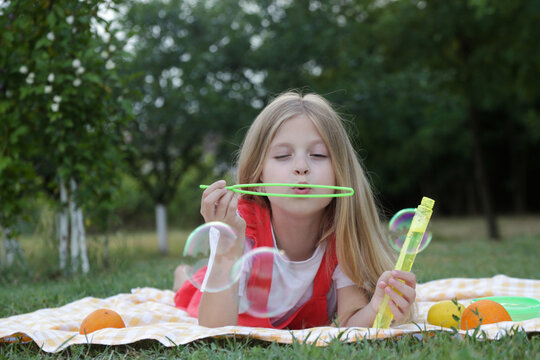 Happy little girl blowing soap bubbles on a sunny summer day