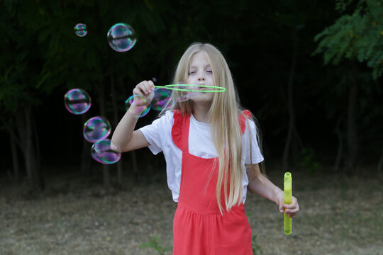 Happy little girl blowing soap bubbles on a sunny summer day