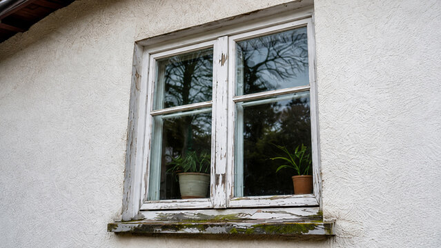 Old weathered wooden window with peeling paint on residential house exterior